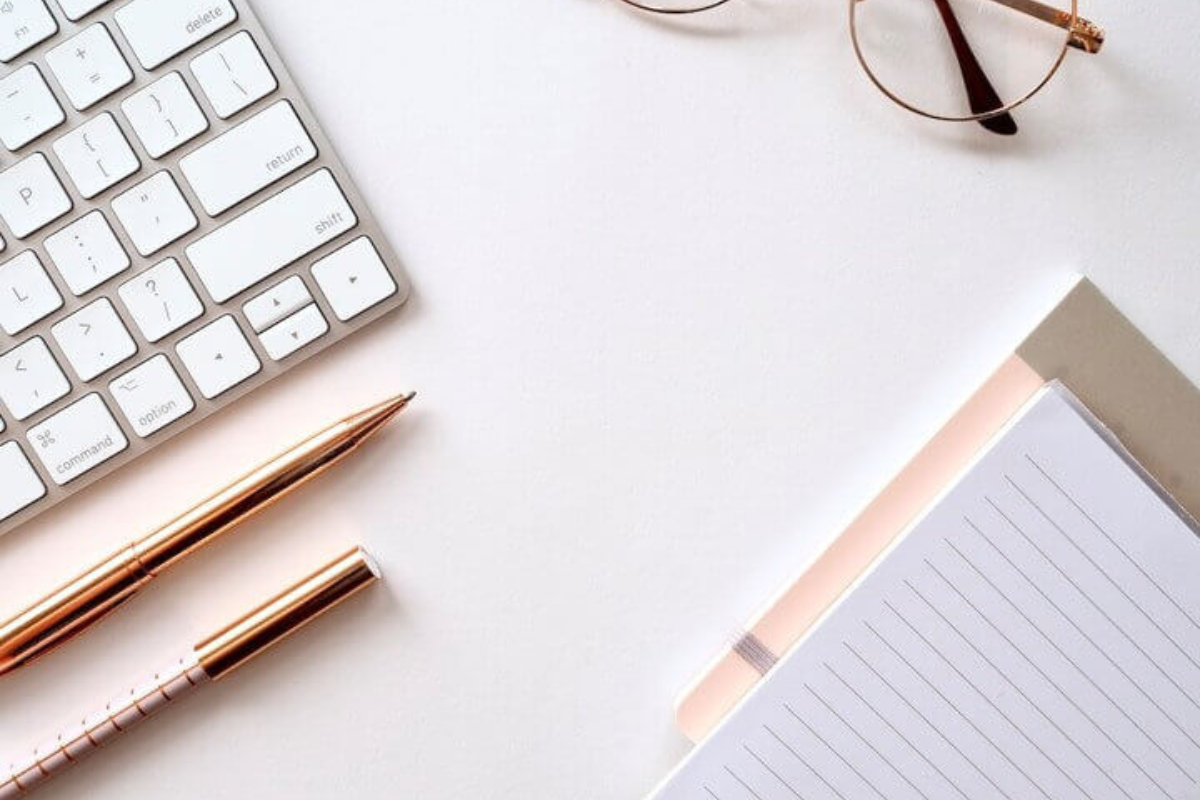 desk with notepad, pen and keyboard