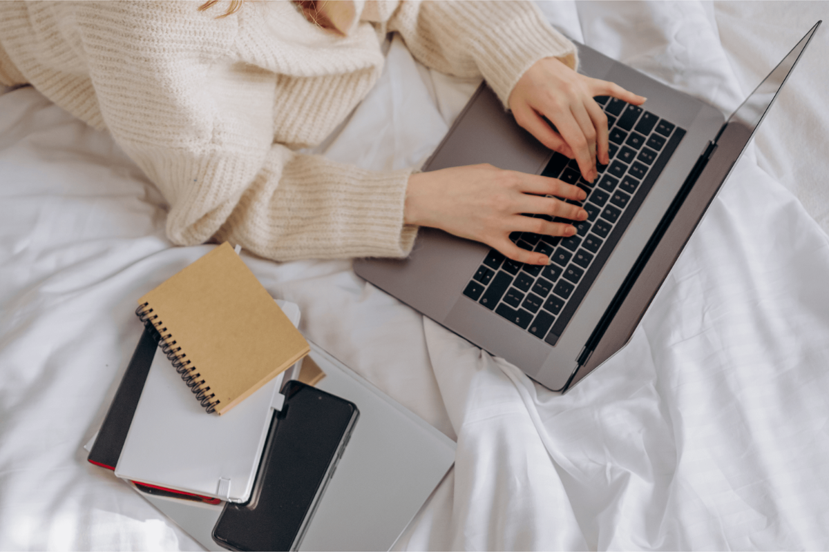 girl typing on laptop lying on bed